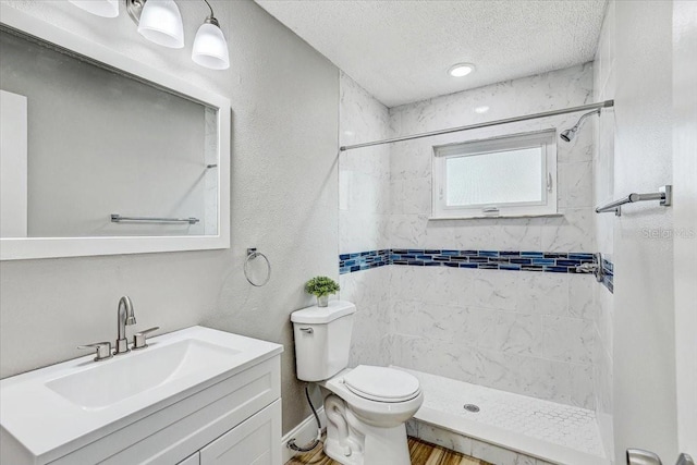 full bathroom featuring a shower stall, toilet, vanity, wood finished floors, and a textured ceiling