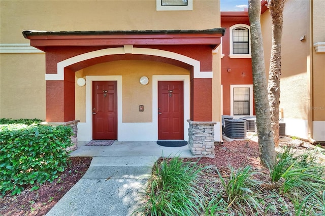 2220 Chianti Pl Unit 8-0828, Palm Harbor, FL 34683 - doorway to property featuring stucco siding, stone siding, and cooling unit
