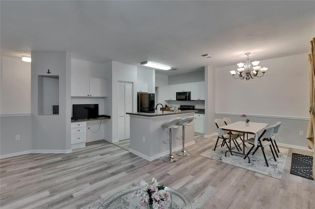 2220 Chianti Pl Unit 8-0828, Palm Harbor, FL 34683 - kitchen with black appliances, light wood-style floors, white cabinets, a sink, and a chandelier
