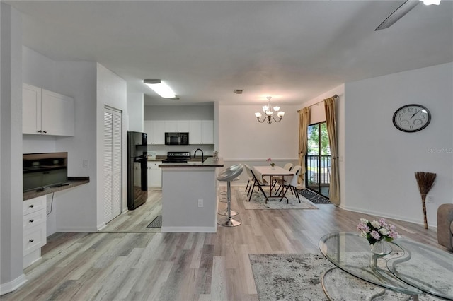 2220 Chianti Pl Unit 8-0828, Palm Harbor, FL 34683 - kitchen featuring black appliances, dark countertops, light wood-style floors, a chandelier, and a sink