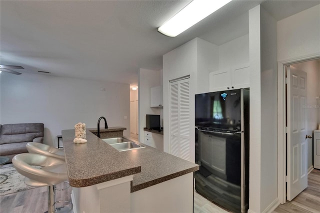 2220 Chianti Pl Unit 8-0828, Palm Harbor, FL 34683 - kitchen featuring freestanding refrigerator, a sink, dark countertops, light wood-style flooring, and white cabinets