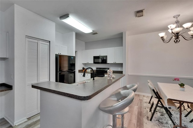 2220 Chianti Pl Unit 8-0828, Palm Harbor, FL 34683 - kitchen with black appliances, a sink, light wood finished floors, dark countertops, and white cabinetry