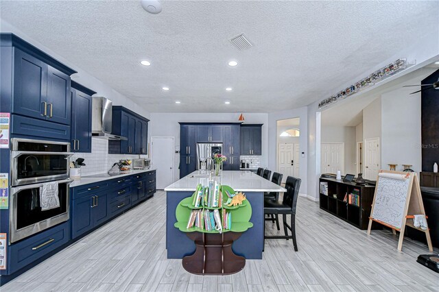 2020 Elk Spring Dr, Brandon, FL 33511 - kitchen featuring wall chimney range hood, light countertops, a kitchen bar, light wood finished floors, and tasteful backsplash