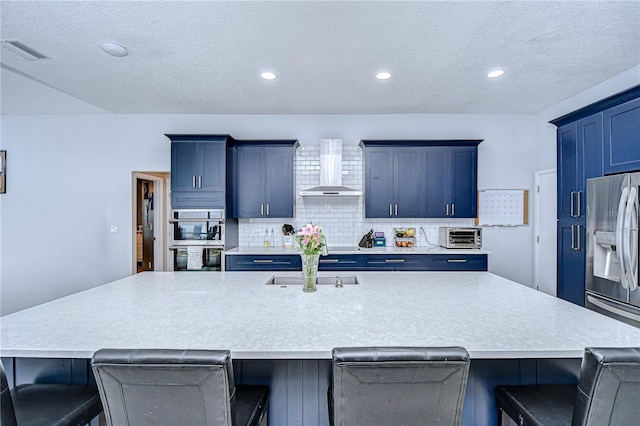 2020 Elk Spring Dr, Brandon, FL 33511 - kitchen featuring wall chimney exhaust hood, appliances with stainless steel finishes, backsplash, a textured ceiling, and a kitchen bar