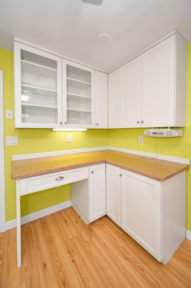 2485 Indigo Dr, Clearwater, FL 33763 - kitchen featuring light wood finished floors, white cabinetry, light stone counters, baseboards, and glass insert cabinets