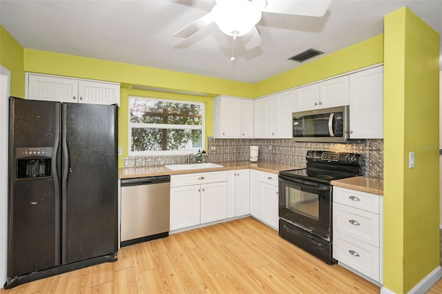 2485 Indigo Dr, Clearwater, FL 33763 - kitchen with black appliances, a sink, white cabinets, light wood finished floors, and decorative backsplash