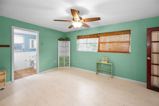2485 Indigo Dr, Clearwater, FL 33763 - unfurnished bedroom featuring wood finished floors, multiple windows, ensuite bathroom, and a ceiling fan