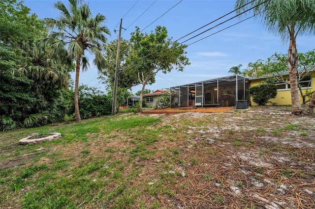 2485 Indigo Dr, Clearwater, FL 33763 - view of green lawn with an outdoor fire pit, a lanai, and central air condition unit