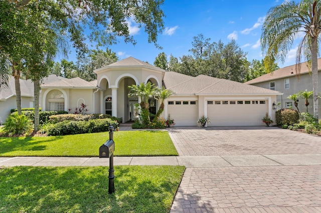 17318 Emerald Chase Dr, Tampa, FL 33647 - mediterranean / spanish home featuring an attached garage, decorative driveway, stucco siding, and a front lawn
