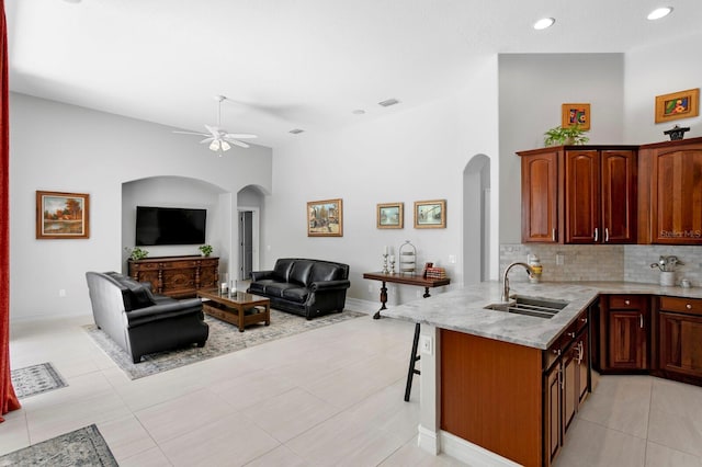 17318 Emerald Chase Dr, Tampa, FL 33647 - kitchen with a sink, arched walkways, a ceiling fan, light stone countertops, and decorative backsplash