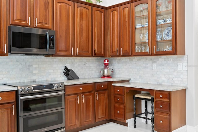 17318 Emerald Chase Dr, Tampa, FL 33647 - kitchen featuring stainless steel appliances, glass insert cabinets, a desk, and light stone countertops