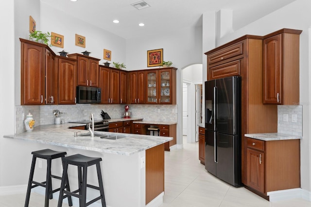 17318 Emerald Chase Dr, Tampa, FL 33647 - kitchen with black fridge with ice dispenser, a peninsula, arched walkways, tasteful backsplash, and recessed lighting