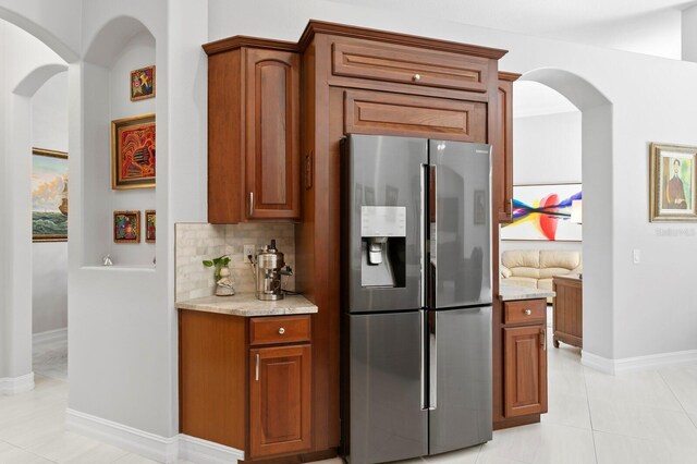 17318 Emerald Chase Dr, Tampa, FL 33647 - kitchen featuring stainless steel fridge with ice dispenser, arched walkways, light tile patterned floors, and tasteful backsplash