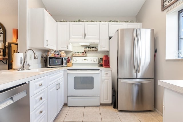 5666 Gardens Dr Unit 202, Sarasota, FL 34243 - kitchen featuring appliances with stainless steel finishes, a sink, light countertops, under cabinet range hood, and white cabinetry