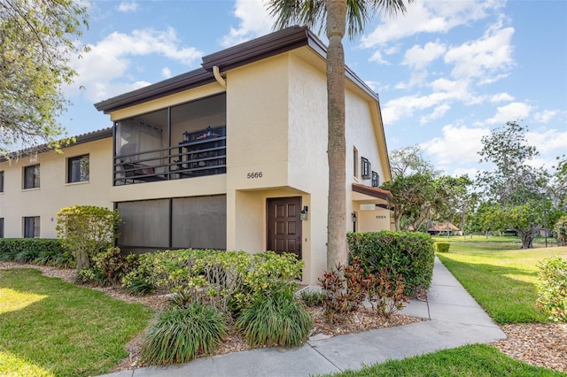 5666 Gardens Dr Unit 202, Sarasota, FL 34243 - view of property exterior with stucco siding and a yard