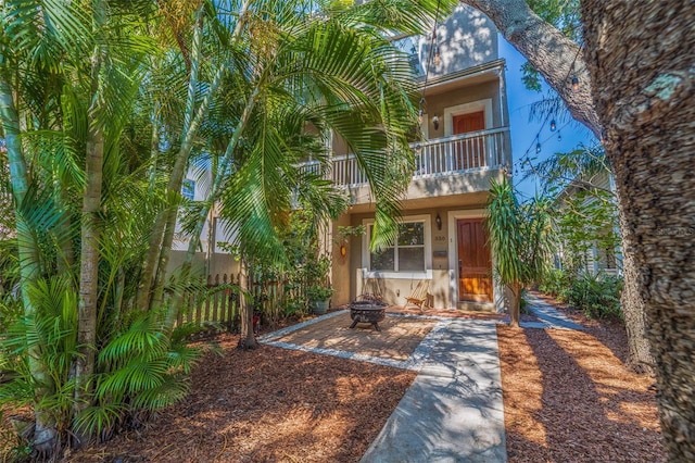 330 Lang Ct N Unit 1, Saint Petersburg, FL 33701 - view of front facade featuring a balcony, stucco siding, an outdoor fire pit, and fence