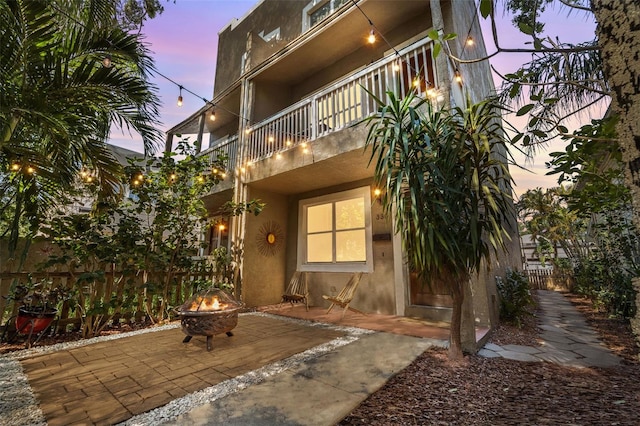 330 Lang Ct N Unit 1, Saint Petersburg, FL 33701 - back of property at dusk with stucco siding, an outdoor fire pit, a balcony, a patio, and fence