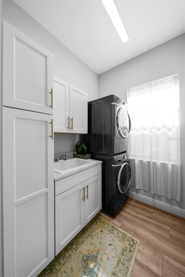12705 Green Heron Way, Odessa, FL 33556 - washroom featuring stacked washer and clothes dryer, cabinet space, and light wood finished floors