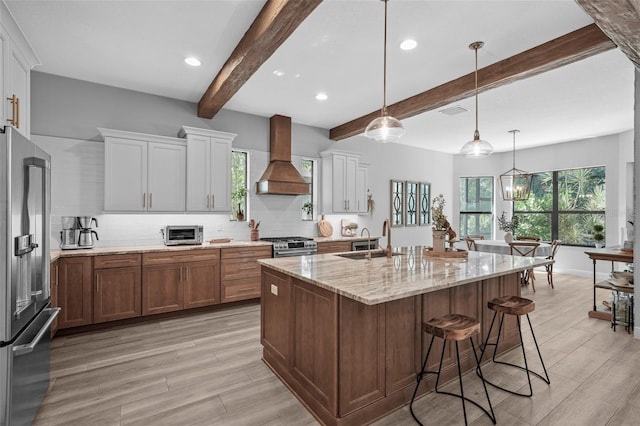 12705 Green Heron Way, Odessa, FL 33556 - kitchen with premium range hood, premium appliances, beamed ceiling, tasteful backsplash, and light wood-style floors