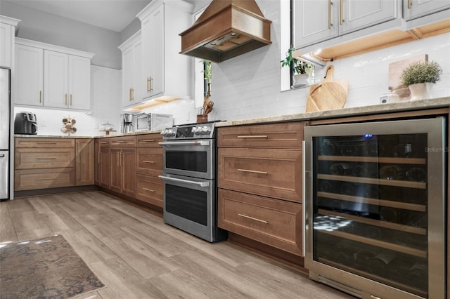 12705 Green Heron Way, Odessa, FL 33556 - kitchen with beverage cooler, appliances with stainless steel finishes, island range hood, and light stone countertops
