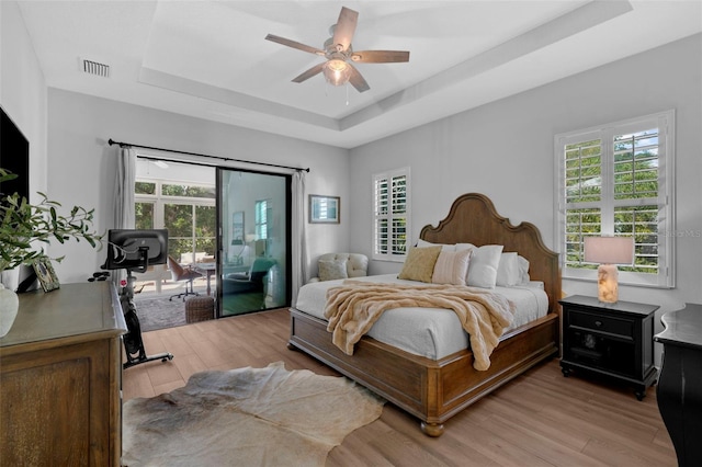 12705 Green Heron Way, Odessa, FL 33556 - bedroom with a tray ceiling, access to exterior, light wood-type flooring, and ceiling fan