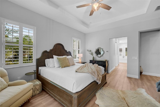 12705 Green Heron Way, Odessa, FL 33556 - bedroom with multiple windows, light wood finished floors, and a tray ceiling