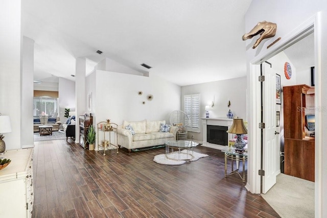 living room featuring healthy amount of natural light, wood finished floors, a fireplace, and vaulted ceiling