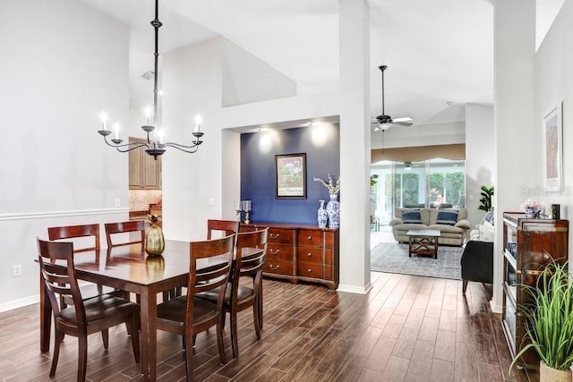 dining area with high vaulted ceiling, dark wood-style flooring, a ceiling fan, a chandelier, and baseboards