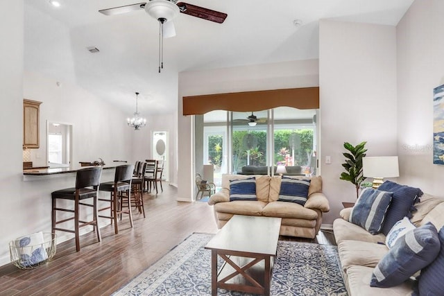 living area with ceiling fan, wood finished floors, high vaulted ceiling, a chandelier, and baseboards