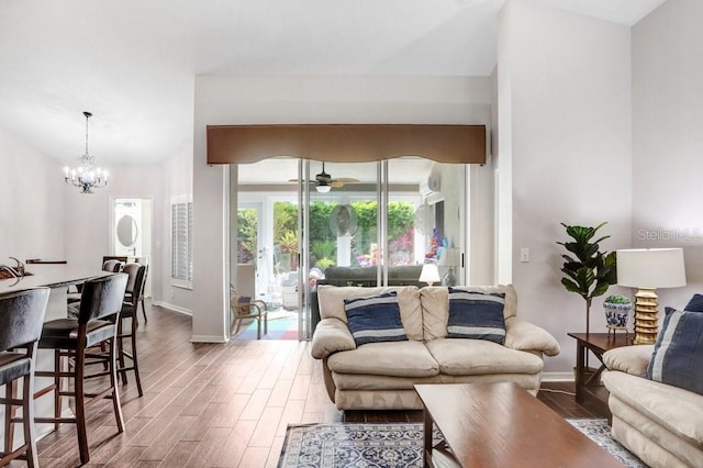 living room featuring wood finished floors, baseboards, a chandelier, and a ceiling fan