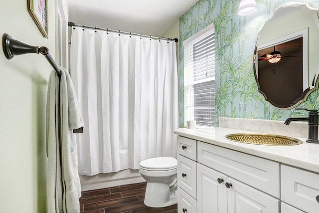 full bath featuring wallpapered walls, wood finished floors, toilet, vanity, and a ceiling fan