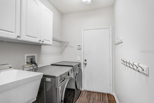 laundry room featuring cabinet space, dark wood-style floors, washing machine and dryer, and baseboards
