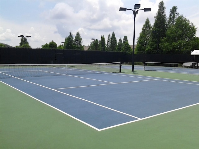 view of tennis court featuring community basketball court and fence