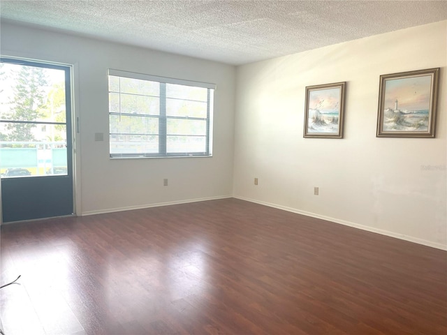 unfurnished room featuring dark wood-style floors, a textured ceiling, and healthy amount of natural light