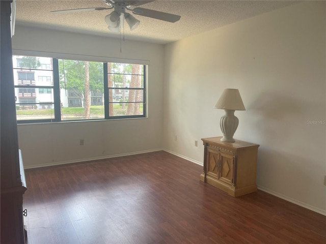 empty room with ceiling fan, wood finished floors, a textured ceiling, and baseboards