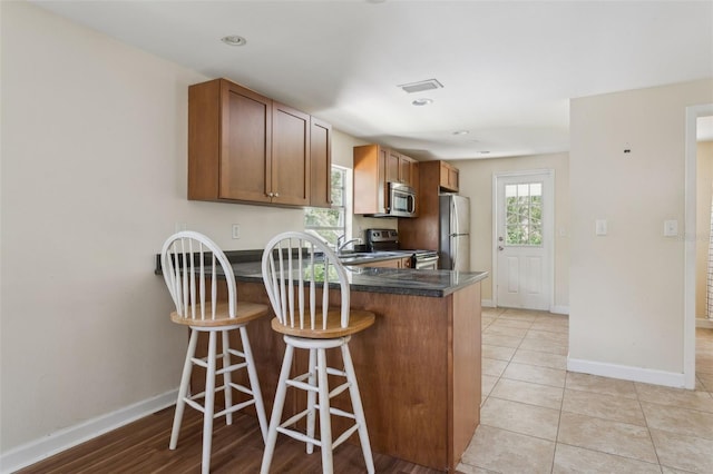 2814 W Humphrey St, Tampa, FL 33614 - kitchen featuring appliances with stainless steel finishes, a peninsula, dark countertops, and baseboards