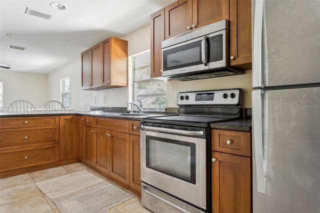 2814 W Humphrey St, Tampa, FL 33614 - kitchen featuring stainless steel appliances, a sink, brown cabinets, and light tile patterned floors