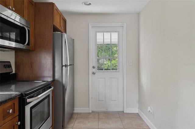 2814 W Humphrey St, Tampa, FL 33614 - kitchen featuring stainless steel appliances, dark countertops, light tile patterned floors, brown cabinets, and baseboards