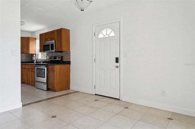 2814 W Humphrey St, Tampa, FL 33614 - kitchen with stainless steel appliances, dark countertops, backsplash, baseboards, and healthy amount of natural light