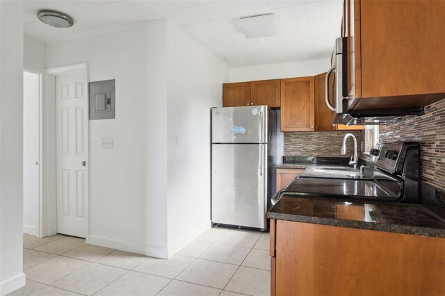 2814 W Humphrey St, Tampa, FL 33614 - kitchen featuring appliances with stainless steel finishes, electric panel, tasteful backsplash, brown cabinetry, and light tile patterned flooring
