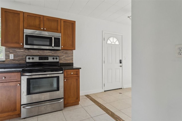 2814 W Humphrey St, Tampa, FL 33614 - kitchen featuring appliances with stainless steel finishes, light tile patterned floors, backsplash, and dark countertops