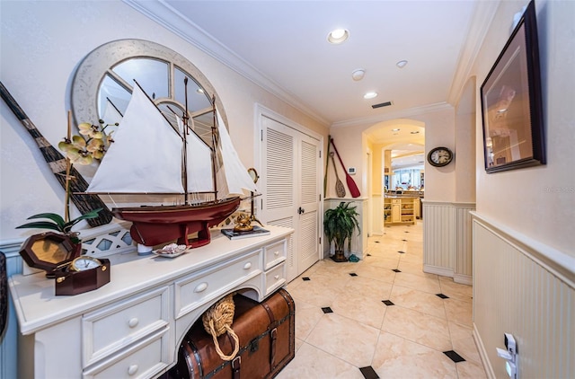corridor featuring wainscoting, arched walkways, ornamental molding, recessed lighting, and light tile patterned flooring