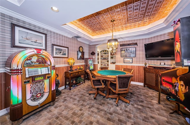 playroom featuring a raised ceiling, wallpapered walls, brick patterned flooring, crown molding, and a wainscoted wall