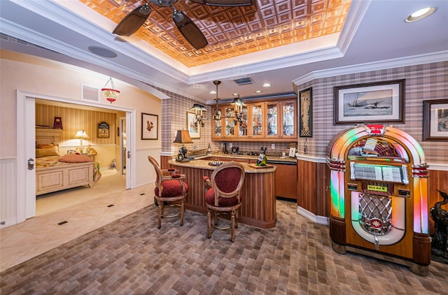 indoor wet bar with a tray ceiling, crown molding, hanging light fixtures, wainscoting, and recessed lighting