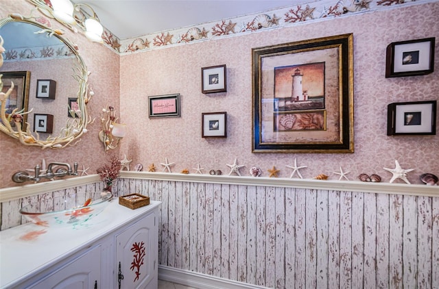 bathroom featuring wallpapered walls, wainscoting, and vanity