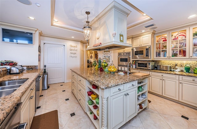 kitchen featuring a raised ceiling, open shelves, stainless steel microwave, cream cabinetry, and crown molding