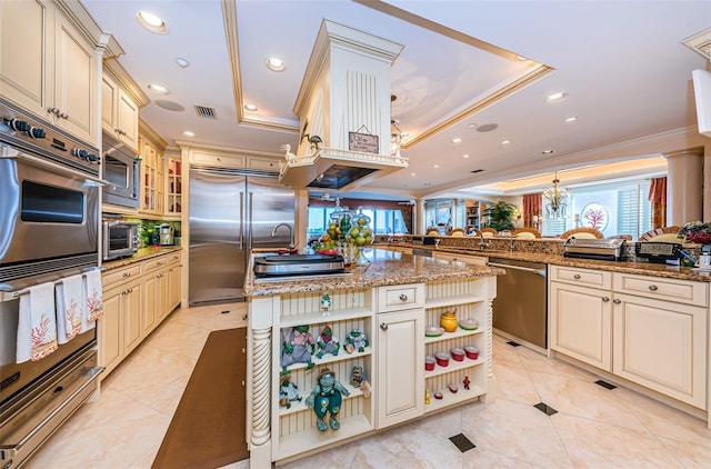 kitchen featuring cream cabinets, built in appliances, a tray ceiling, crown molding, and recessed lighting