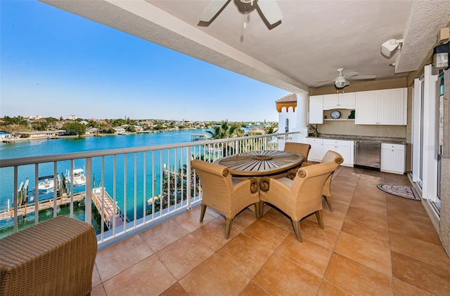 balcony featuring a ceiling fan, exterior kitchen, and a water view