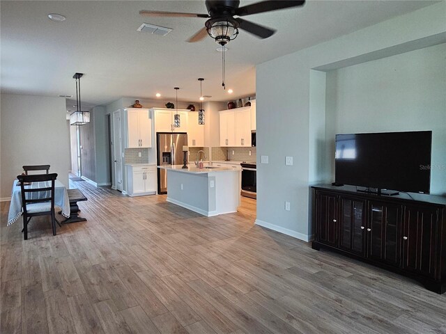 3776 Maxwell Park Dr, Sun City Center, FL 33573 - kitchen featuring stainless steel fridge with ice dispenser, light countertops, ceiling fan, decorative backsplash, and an island with sink