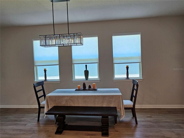 3776 Maxwell Park Dr, Sun City Center, FL 33573 - dining space featuring baseboards, wood finished floors, and a chandelier